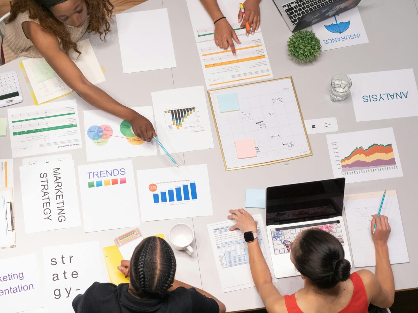 Top-down view of people working together at a table with various documents and charts.