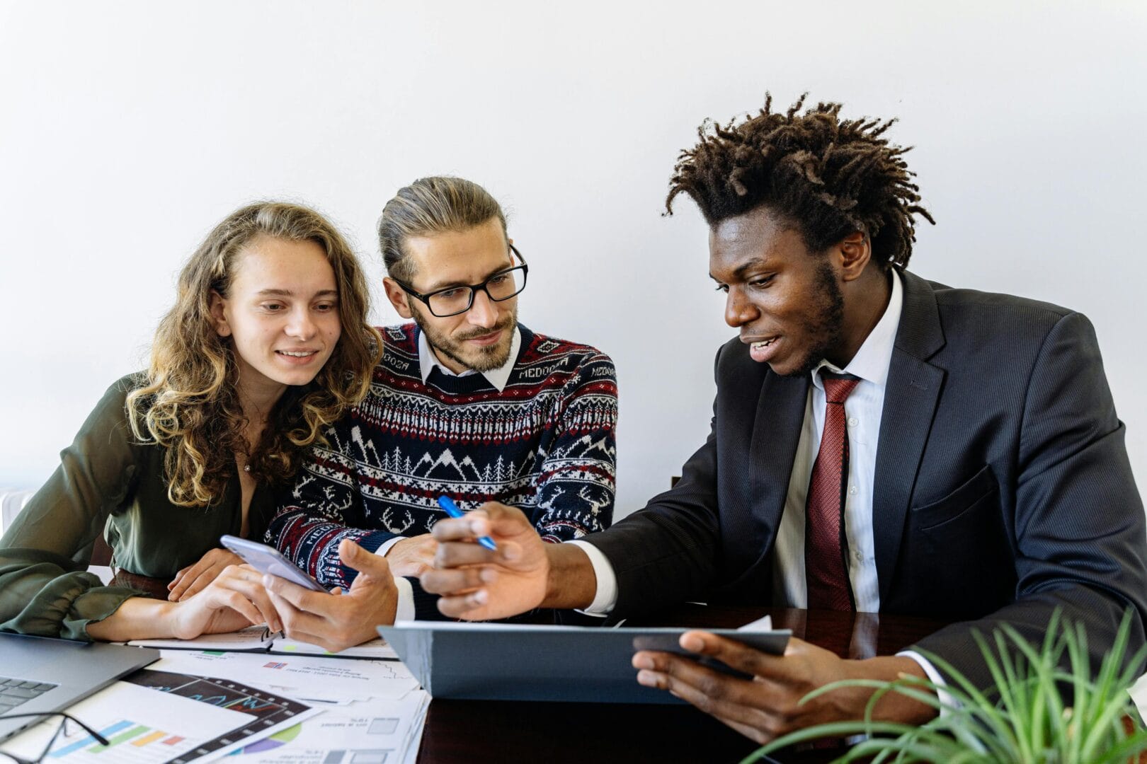Three people sitting at a table, reviewing documents and working together.
