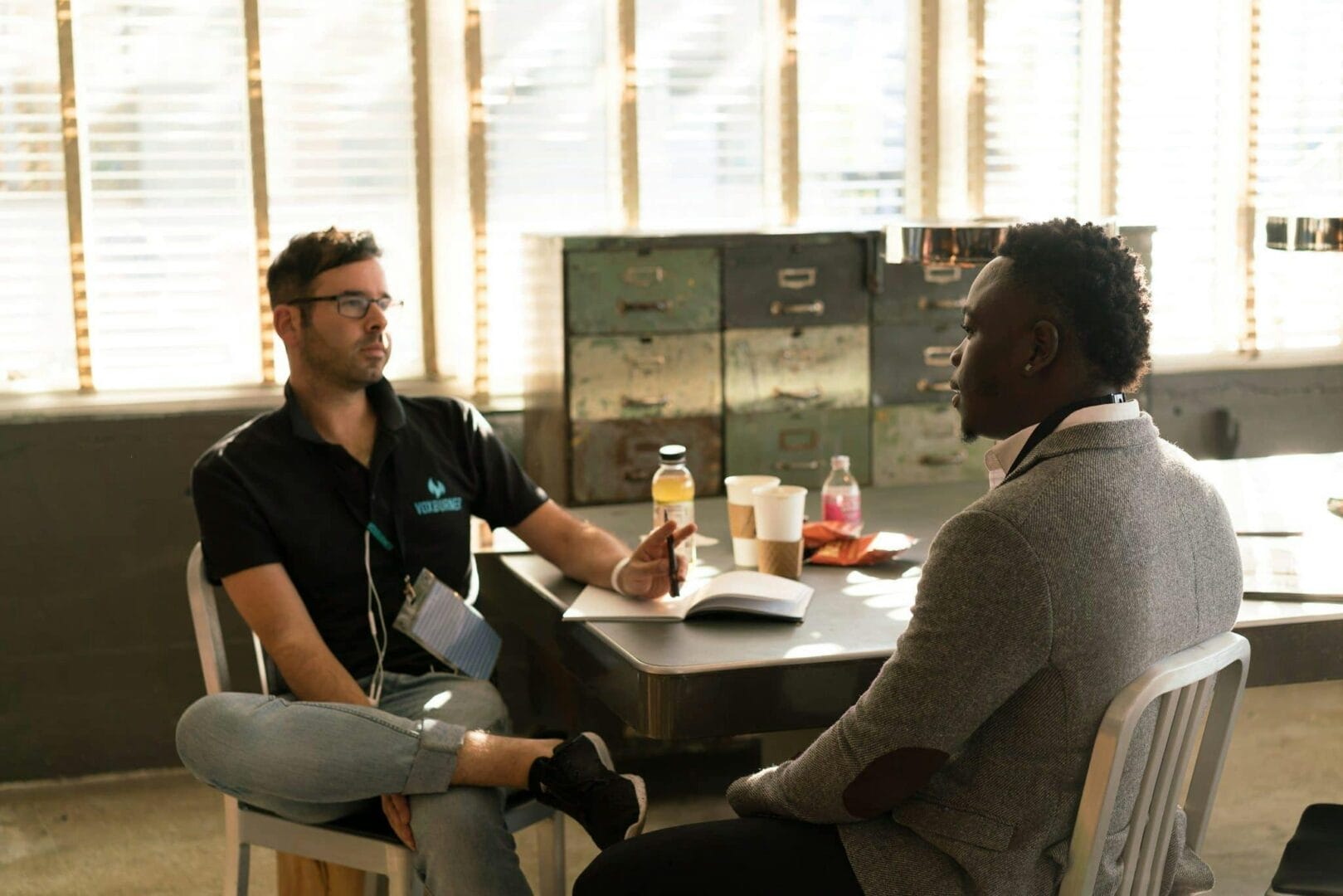 Two people sitting at a table in a casual setting, having a conversation.