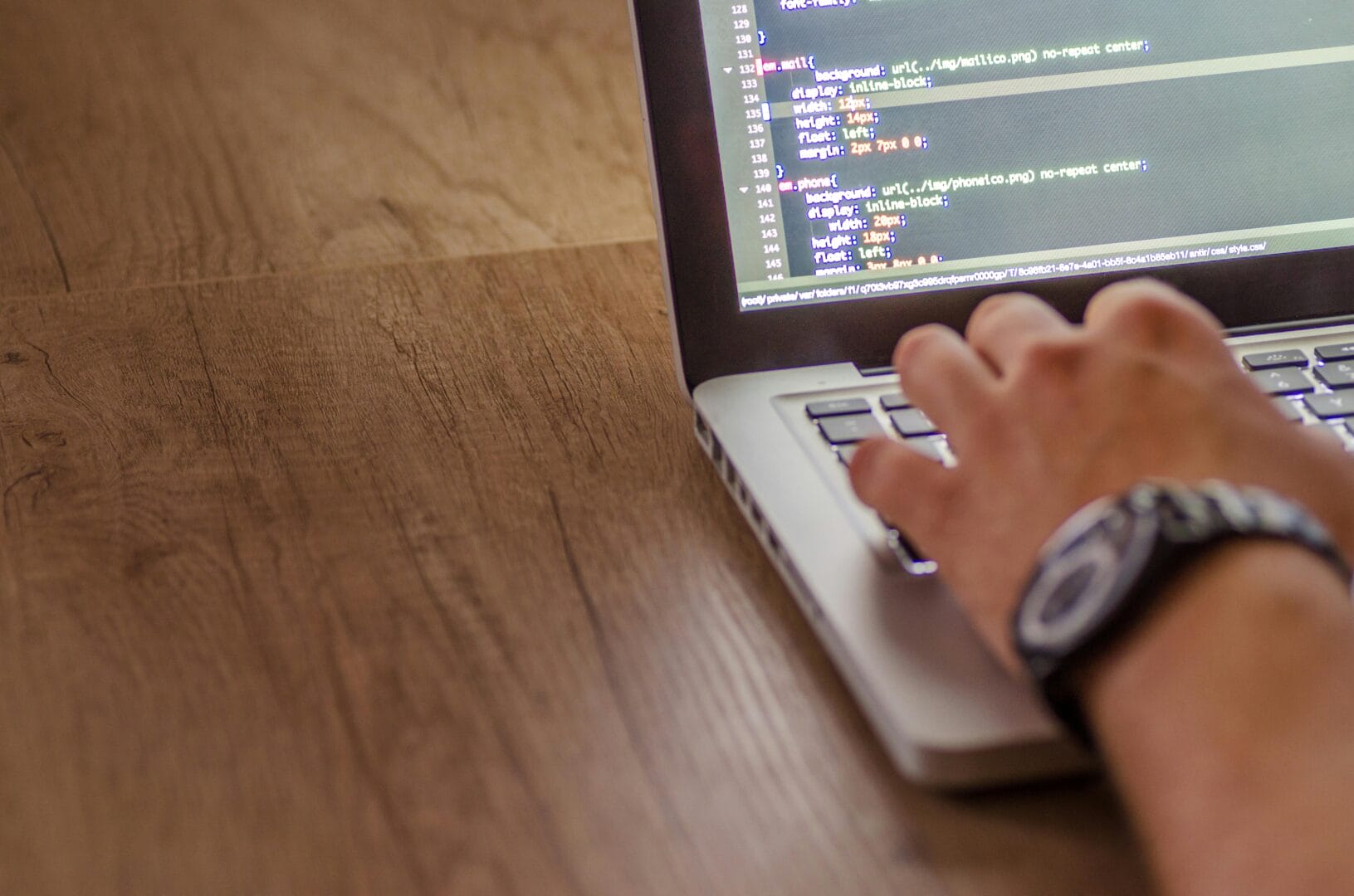 Person typing on a laptop with code on the screen.