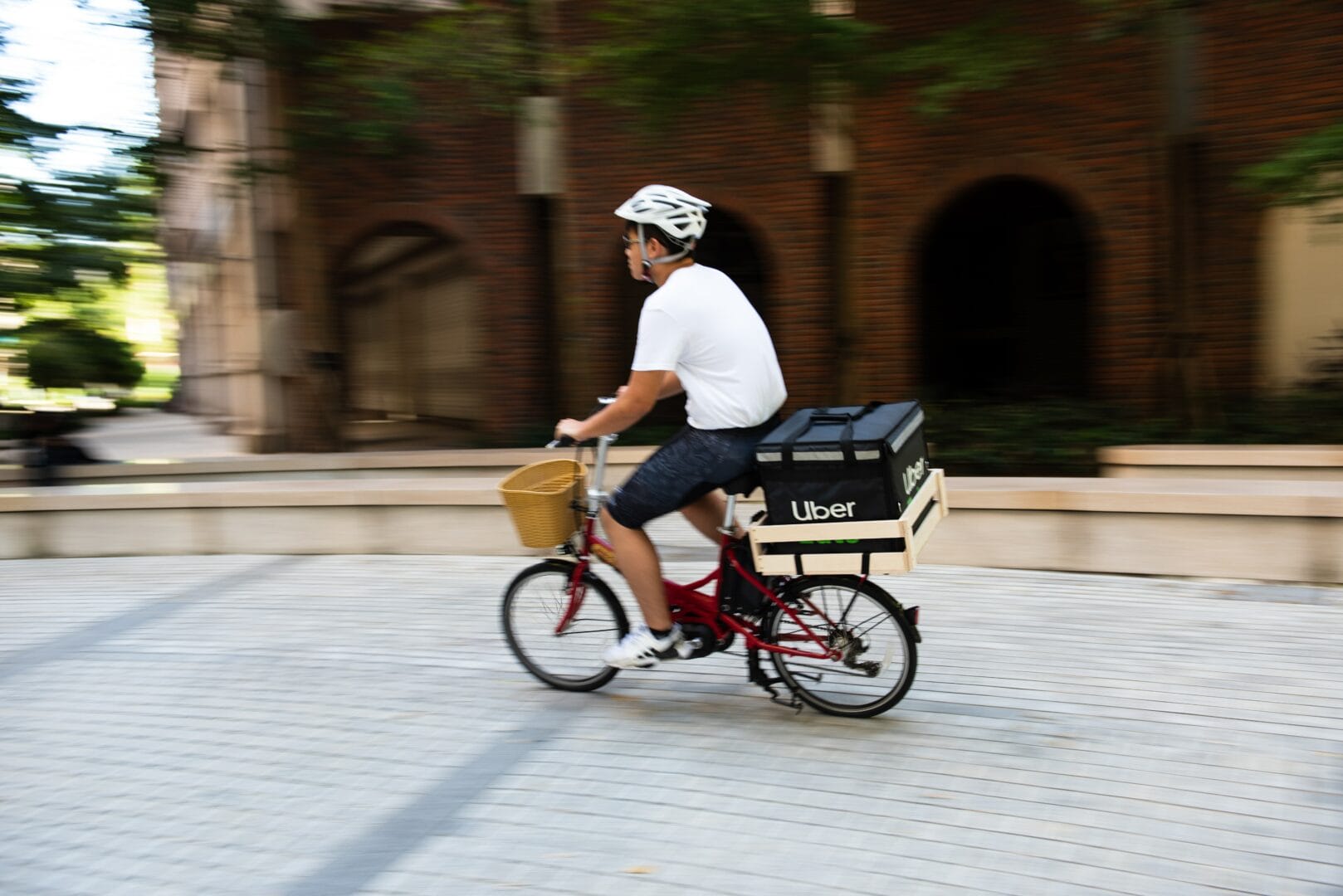 Person riding a bicycle with an Uber Eats delivery box on the back.