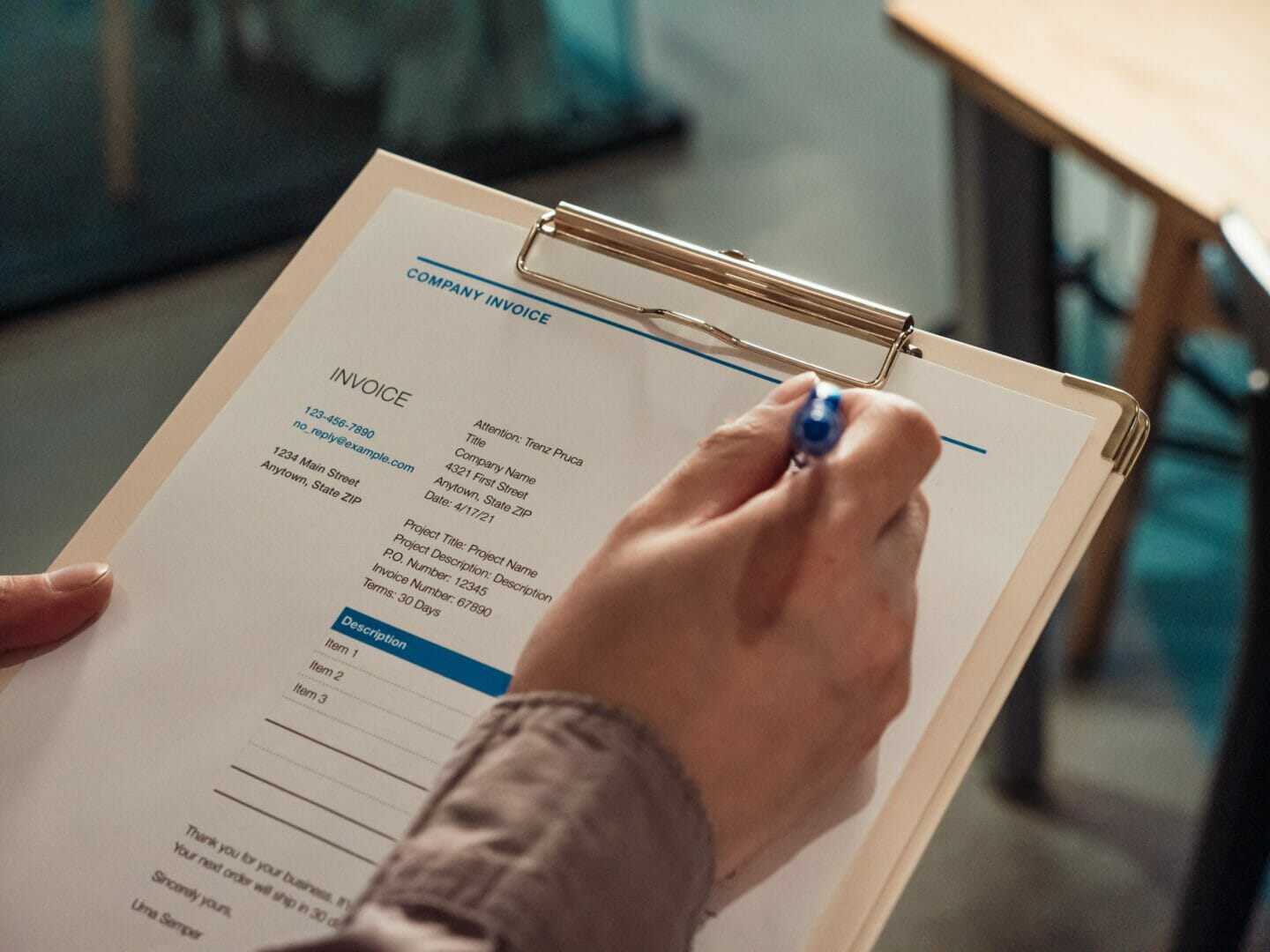 Person writing on a document attached to a clipboard