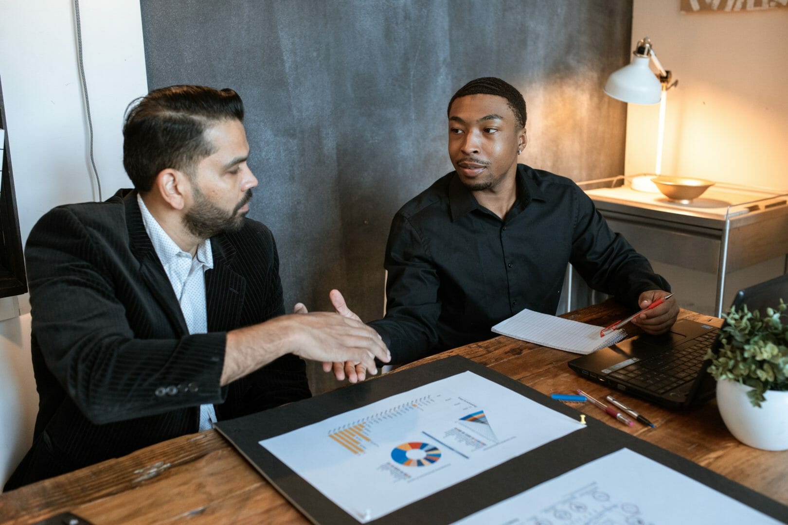 Two men sitting at a table discussing documents