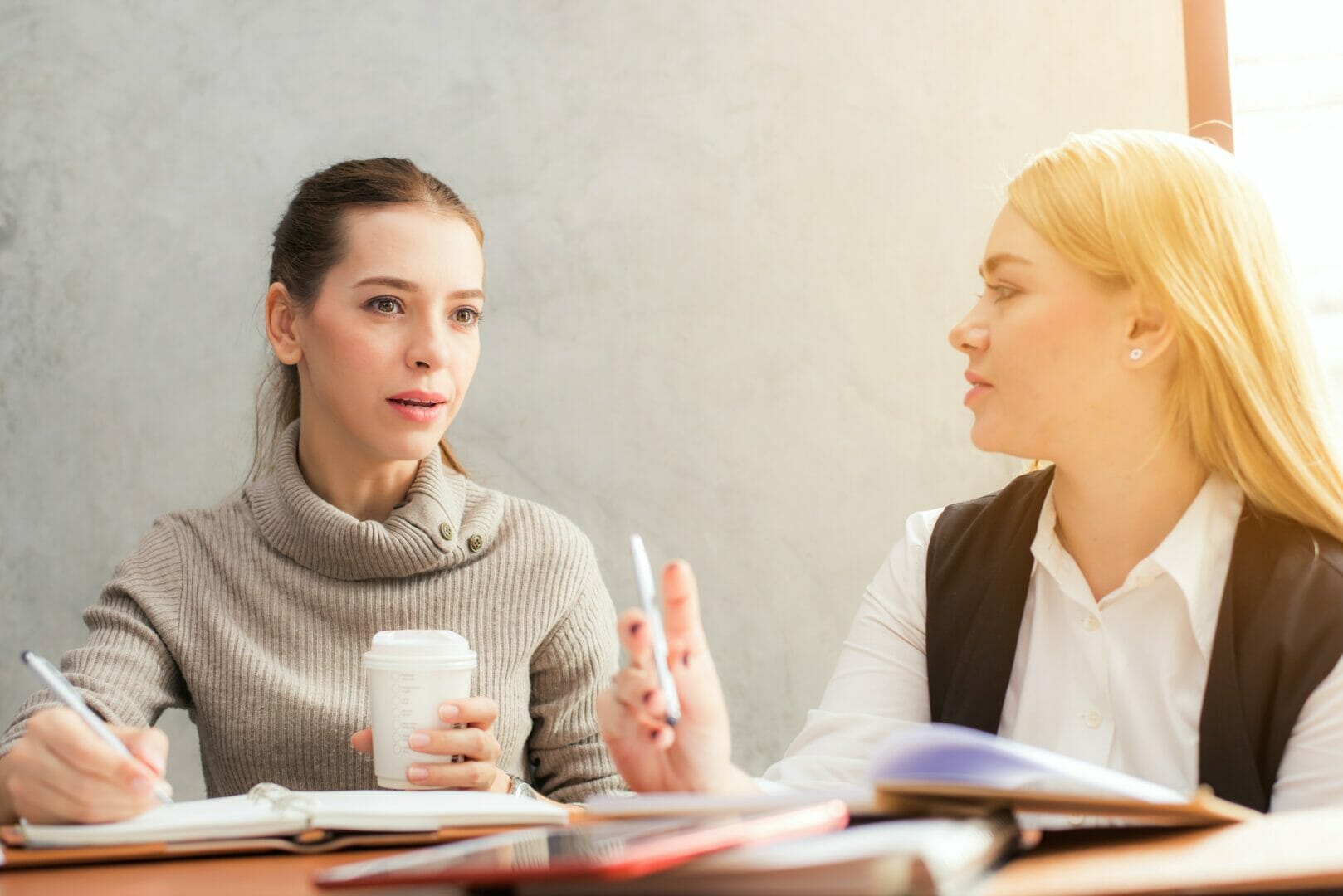 Two people having a conversation, one holding a coffee cup