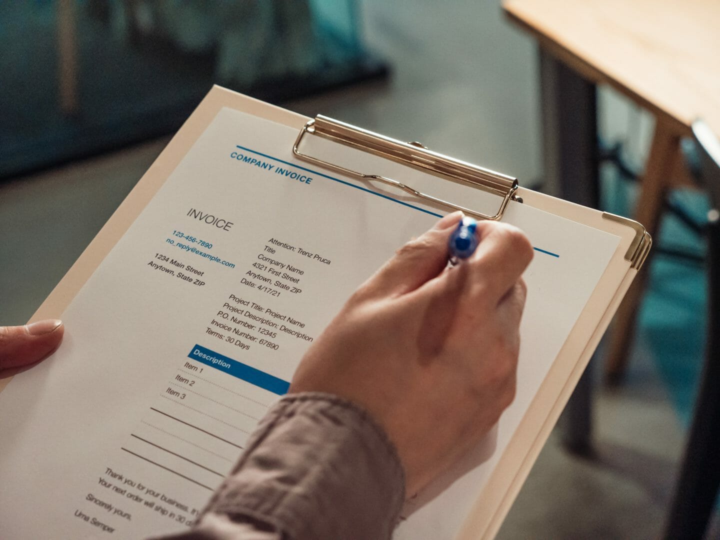 Person holding a clipboard and filling out an invoice form