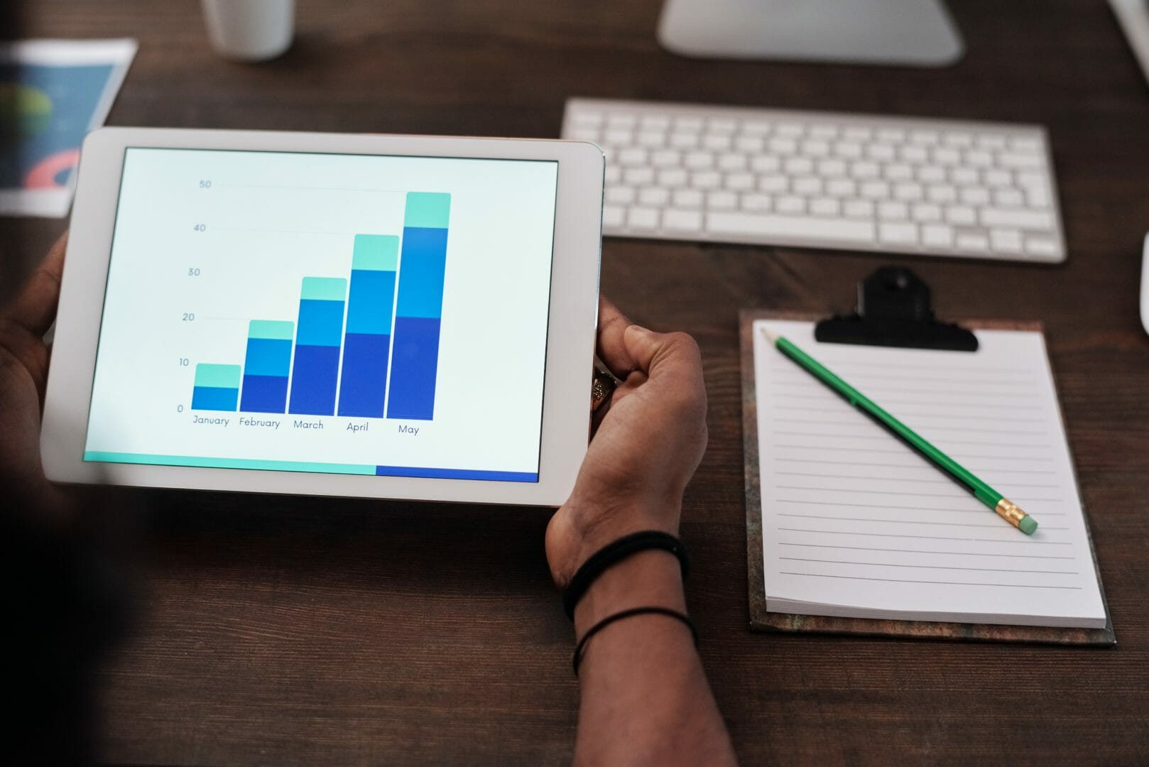 Person holding a tablet displaying a bar chart