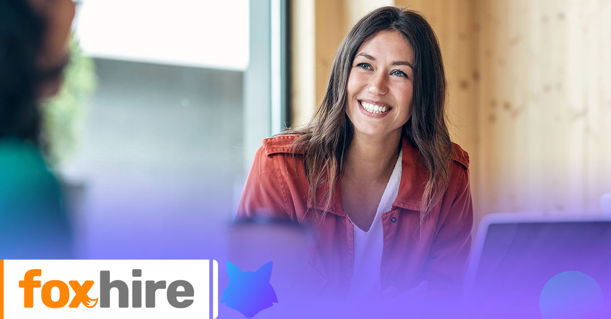 Smiling woman in a professional setting with the foxhire logo in the bottom left corner