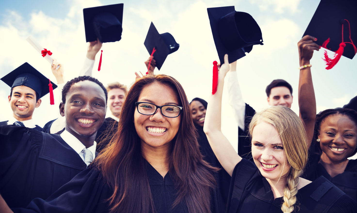 graduation|Group of graduates in caps and gowns, smiling and celebrating