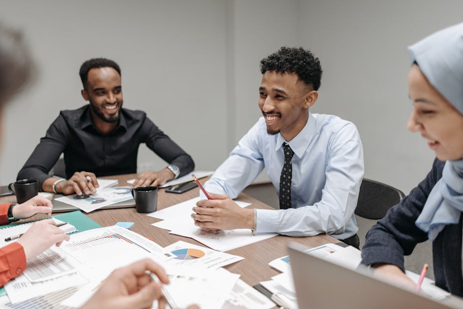 Diverse HR and business team smiling and collaborating around printed charts and reports at a conference table