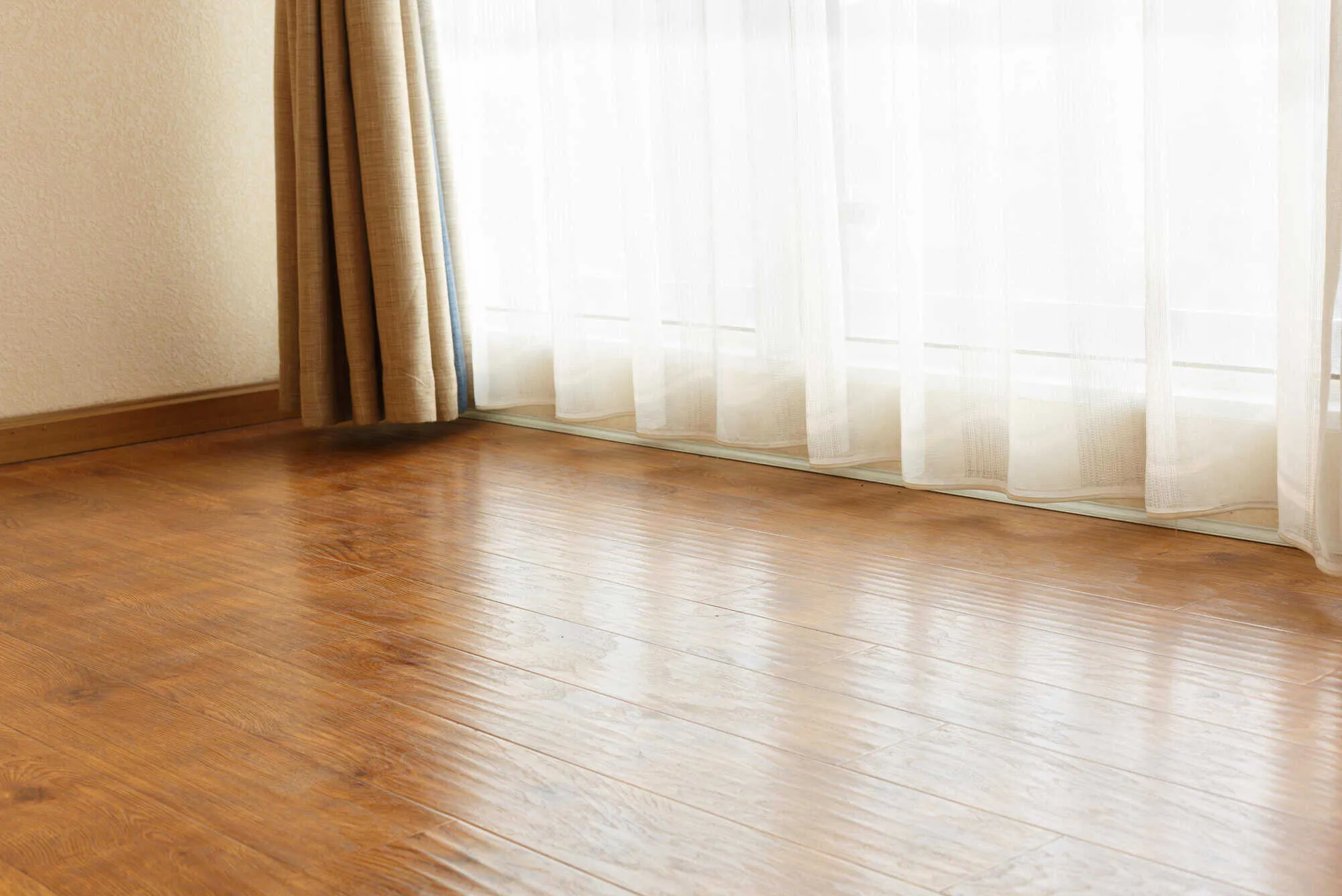 hardwood floor and bright window with sheer curtains