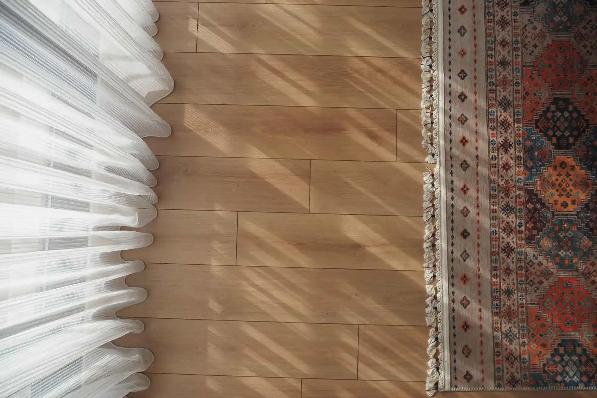 warm sunlight through sheer curtains on light hardwood living room floor