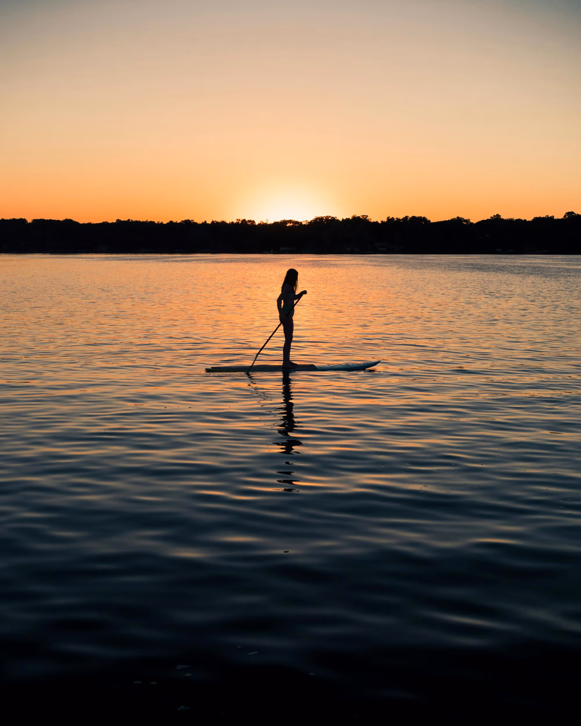 female on a paddleboard during a sunset on a lake