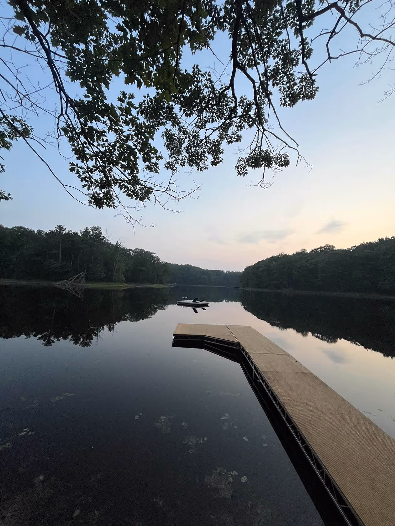 Small wooden dock extending over a peaceful pond, surrounded by trees and natural greenery at Matson Lake Lodge.
