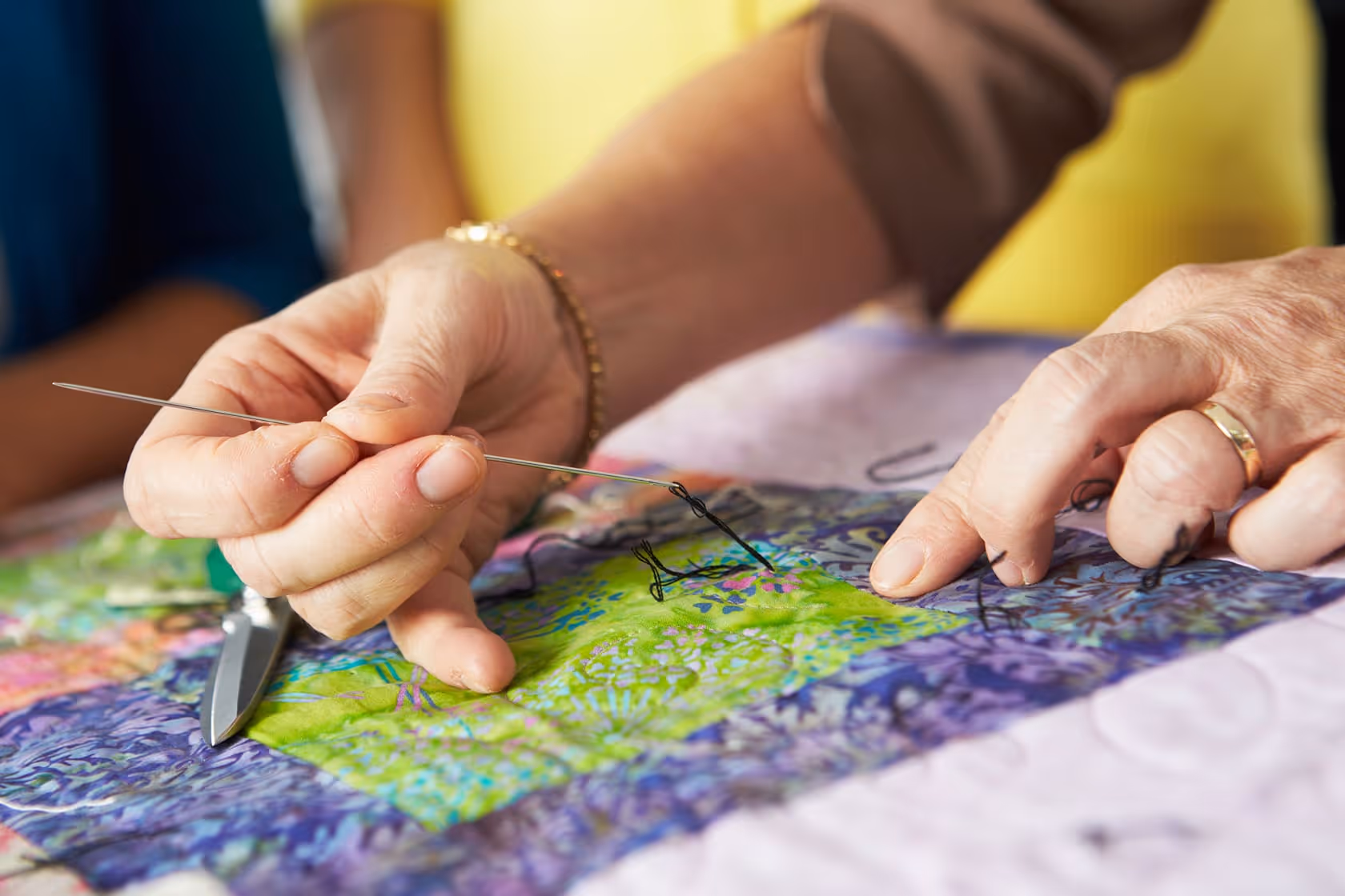 Snow covered trail with a person with a helmet on an orange snowmobile