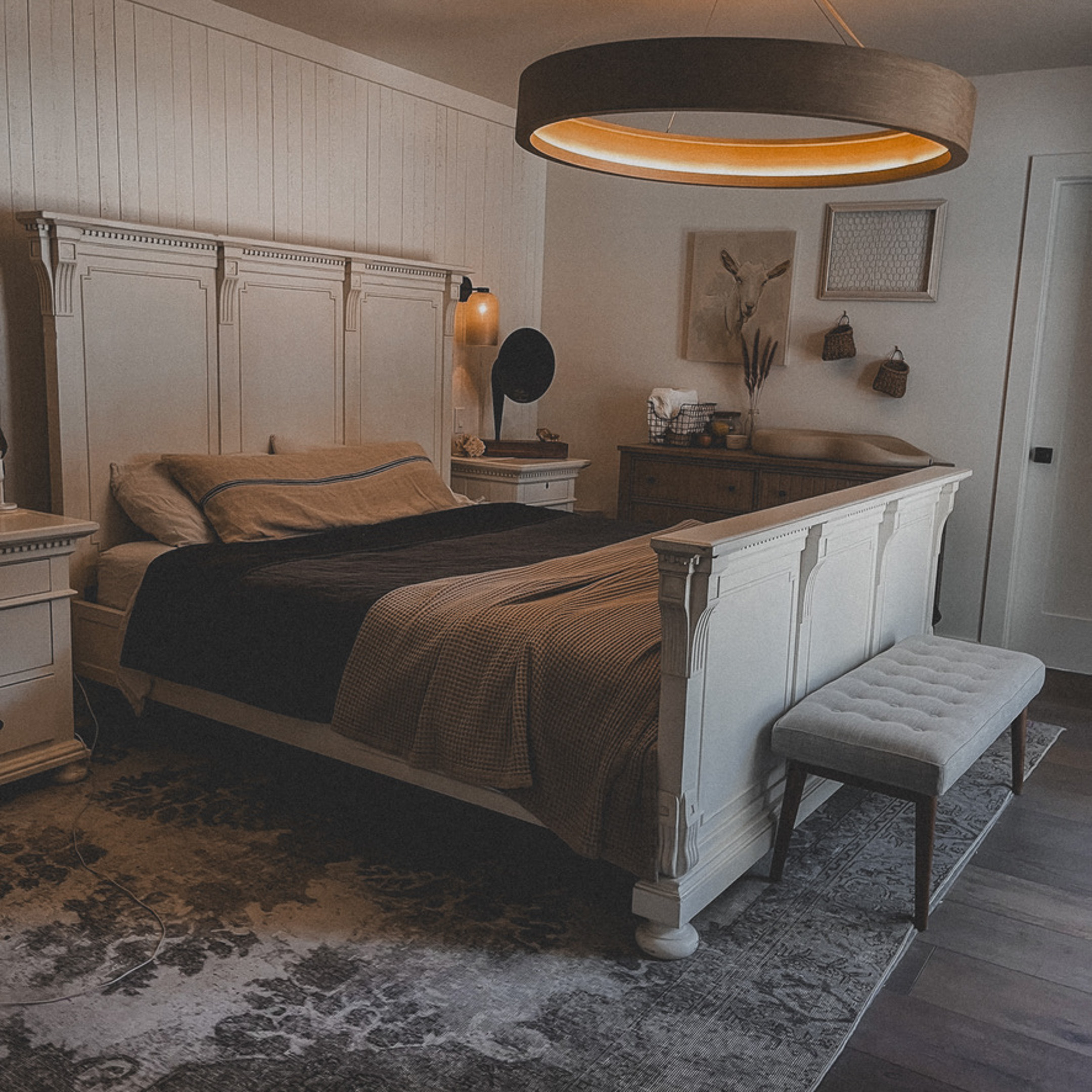 Modern bedroom with white furniture and moody lighting.