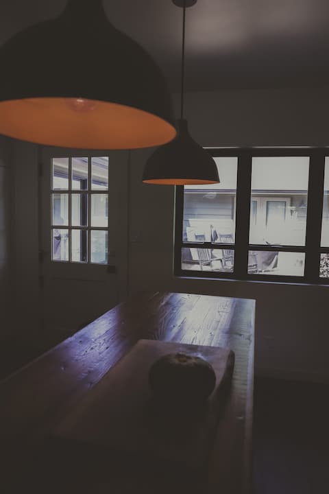 Warm-lit dining table beneath a modern pendant light.