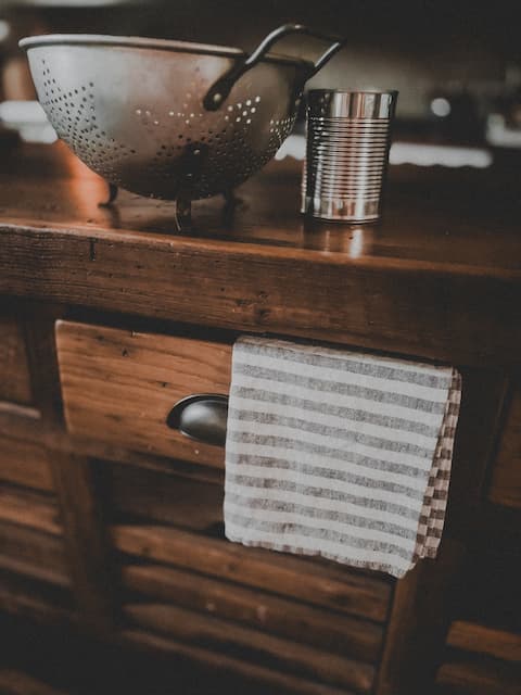 Wooden kitchen counter with a metal bowl and striped towel.