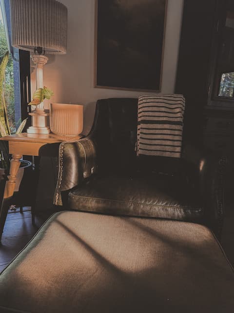 Cozy corner with a leather armchair, lamp, and houseplants.