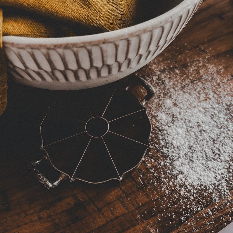 Bowl of food on a wooden counter dusted with flour.