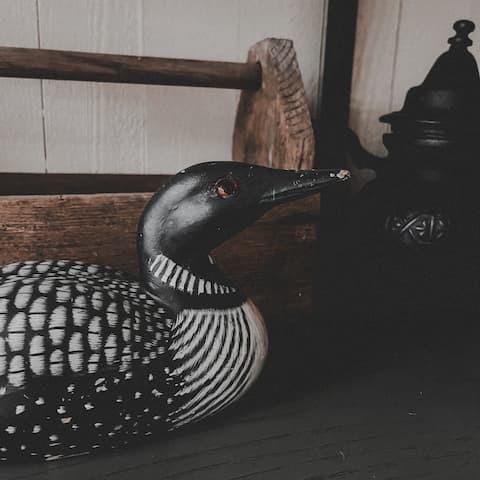Decorative black and white duck sculpture on a bench.