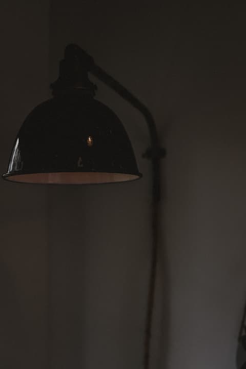 Black industrial-style wall lamp against a dark background.