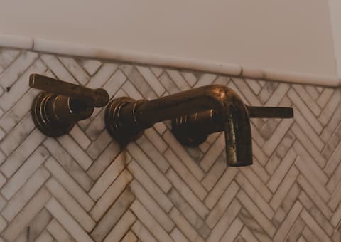 Brass faucet set into a chevron-tiled wall.