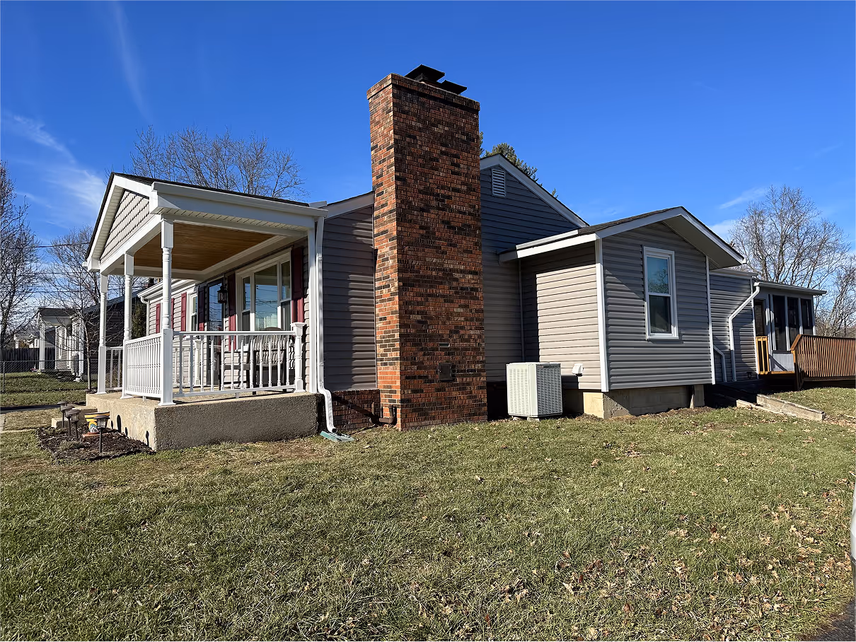 Side of grey house with brick chimney