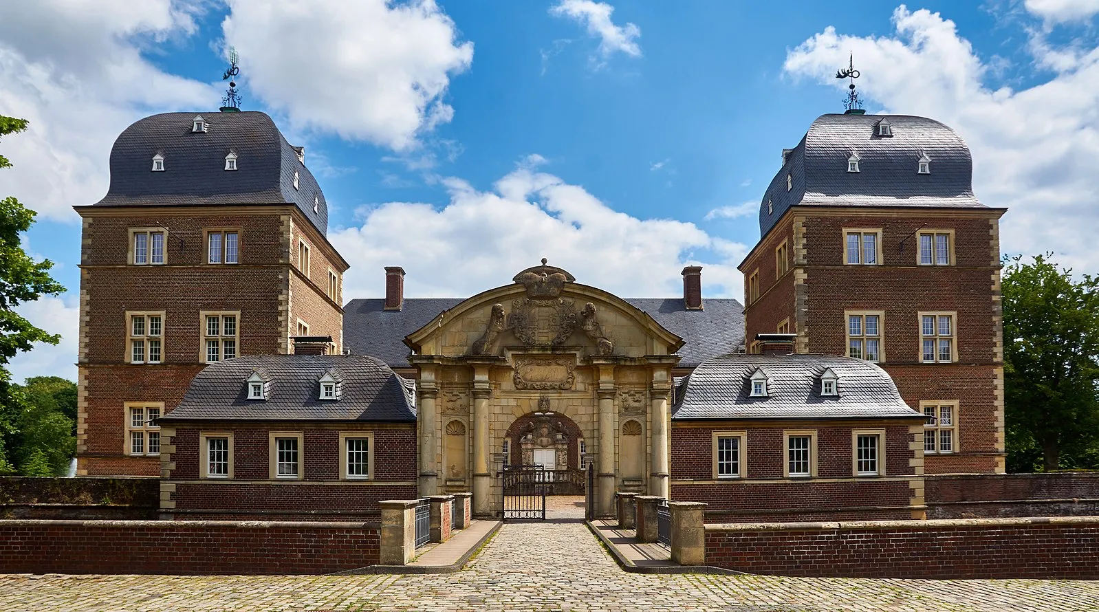 Schloss Ahaus – barockes Hauptportal mit zwei Türmen und Kopfsteinpflaster.