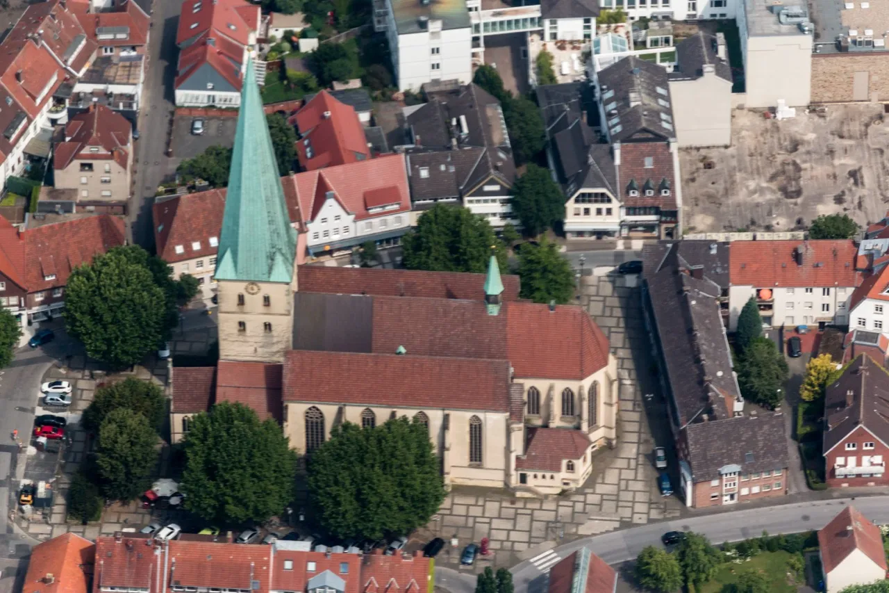 Luftaufnahme der St.-Remigius-Kirche in Borken mit markantem grünen Kirchturm, umgeben von historischen Gebäuden und Straßen.