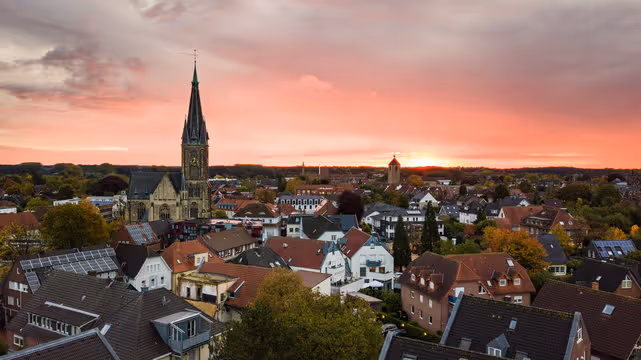 Westfälisches Glockenmuseum in Gescher – moderne Fassade mit Holzoptik, großen Glocken im Außenbereich und Statue im Hintergrund.