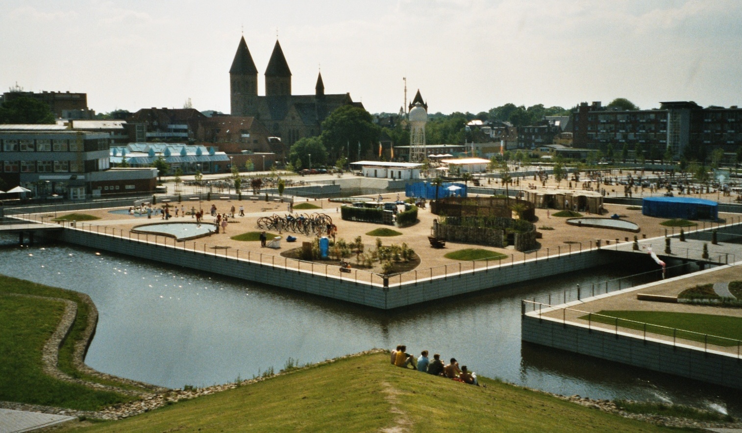 Ansicht des rock’n’popmuseums in Gronau mit moderner Glasfassade und historischer Backsteinhalle, davor eine breite Treppenanlage am Wasser.
