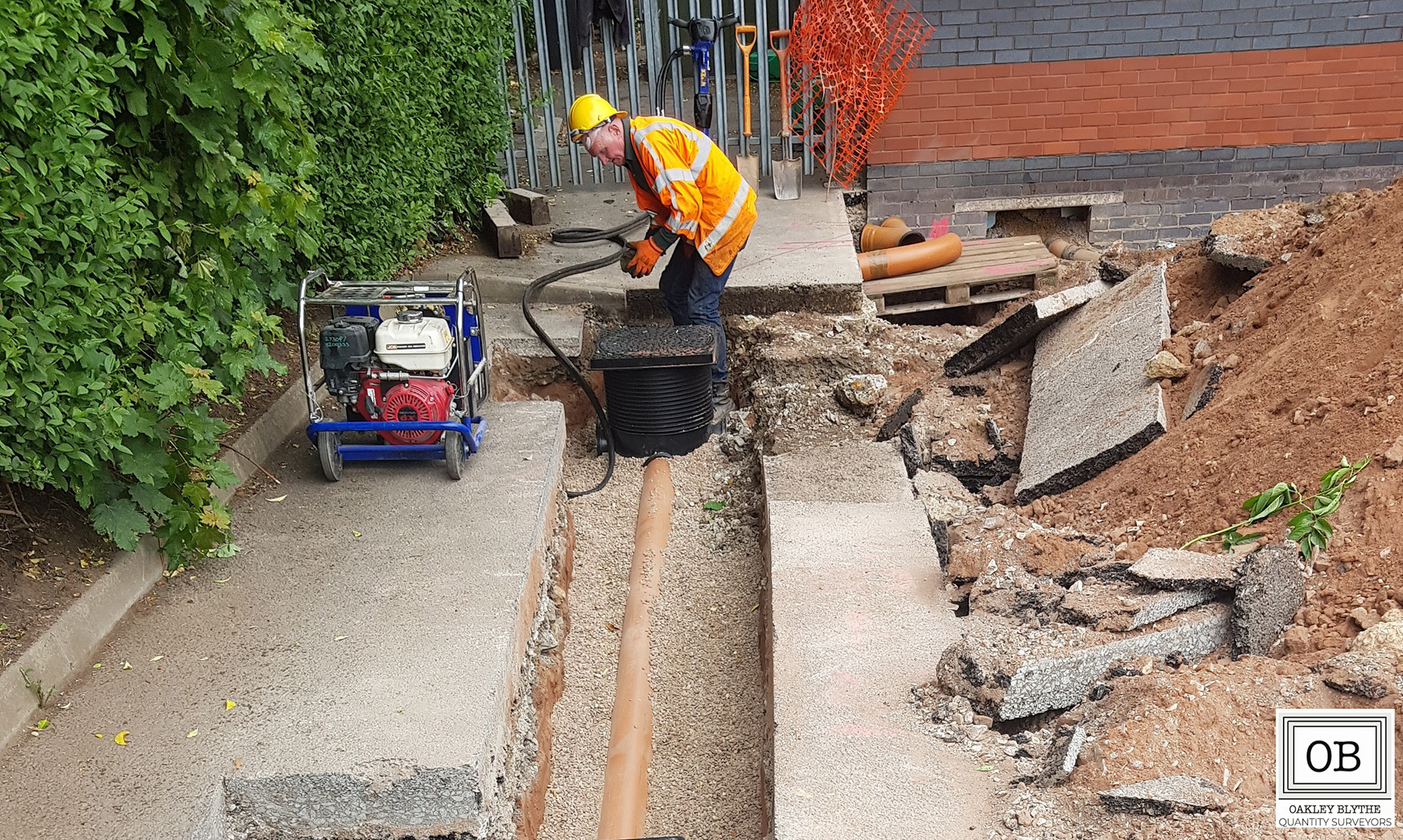 Groundworker fitting an inspection chamber managed by Oakley Blythe Quantity Surveyors of Leamington Spa and Warwick