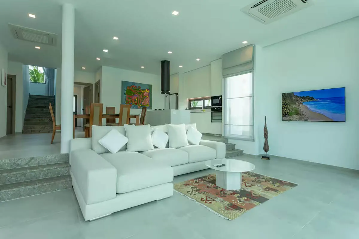Civetta Grand Villa, Най Харн — гостиная с белым диваном и лестницей на второй этаж