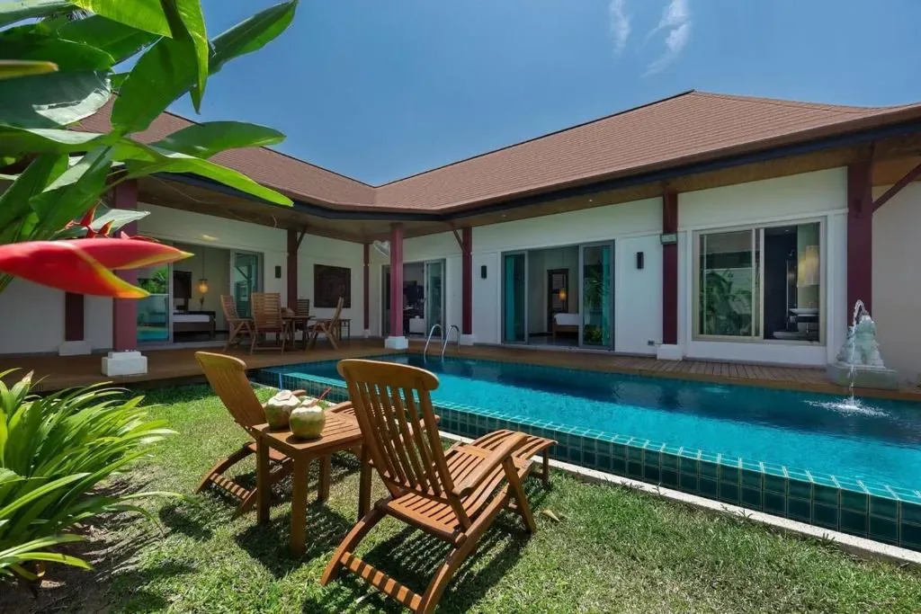 Villa Kokyang, Най Харн — обеденный стол и шезлонги на газоне у бассейна