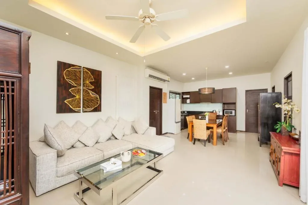 Villa Ikaroa, Най Харн — гостиная с белым диваном и выходом в кухню