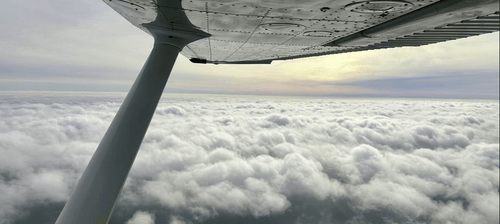 Looking out Cessna window over clouds.