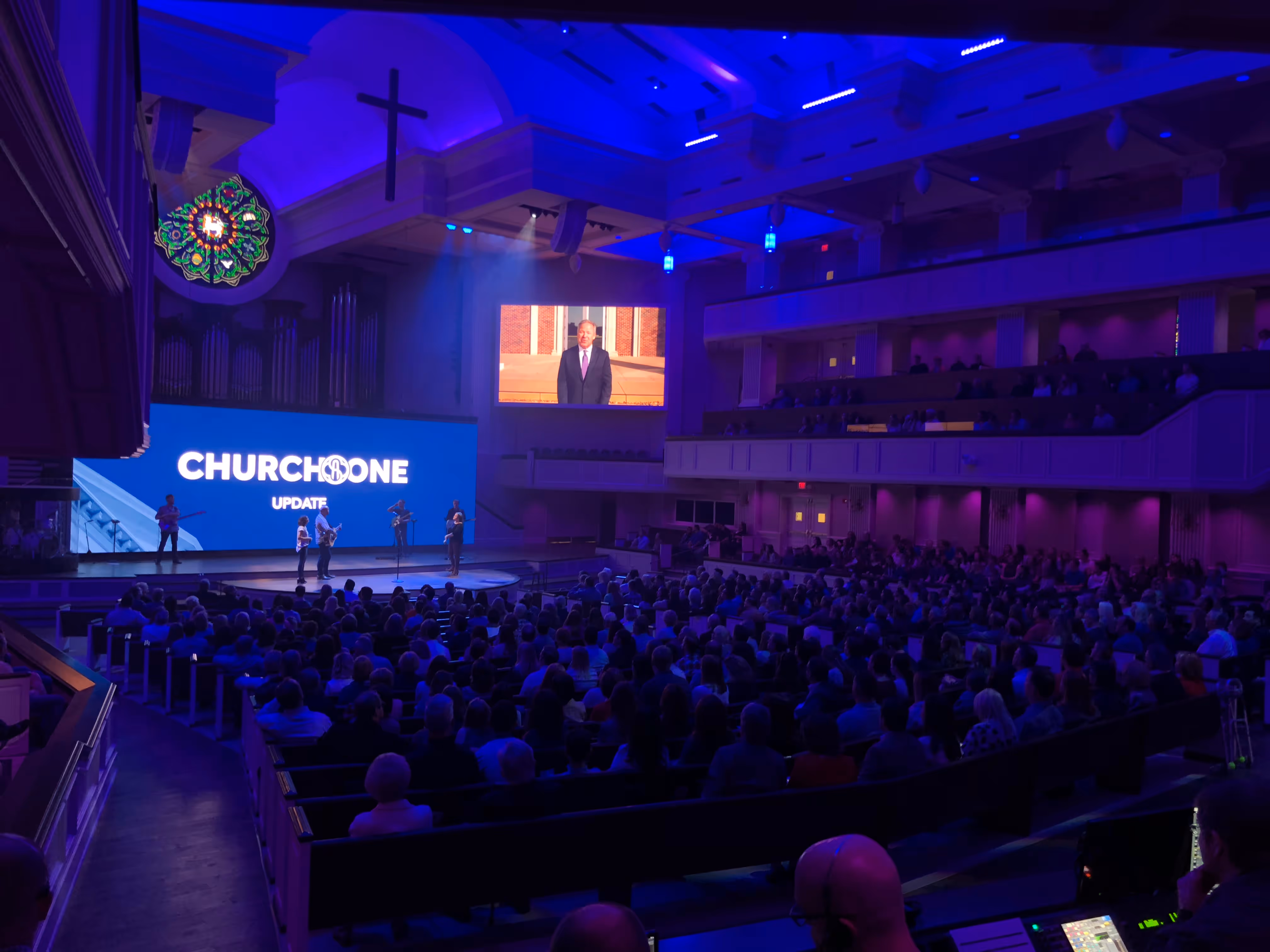 Large auditorium event with stage projection and dynamic blue lighting design