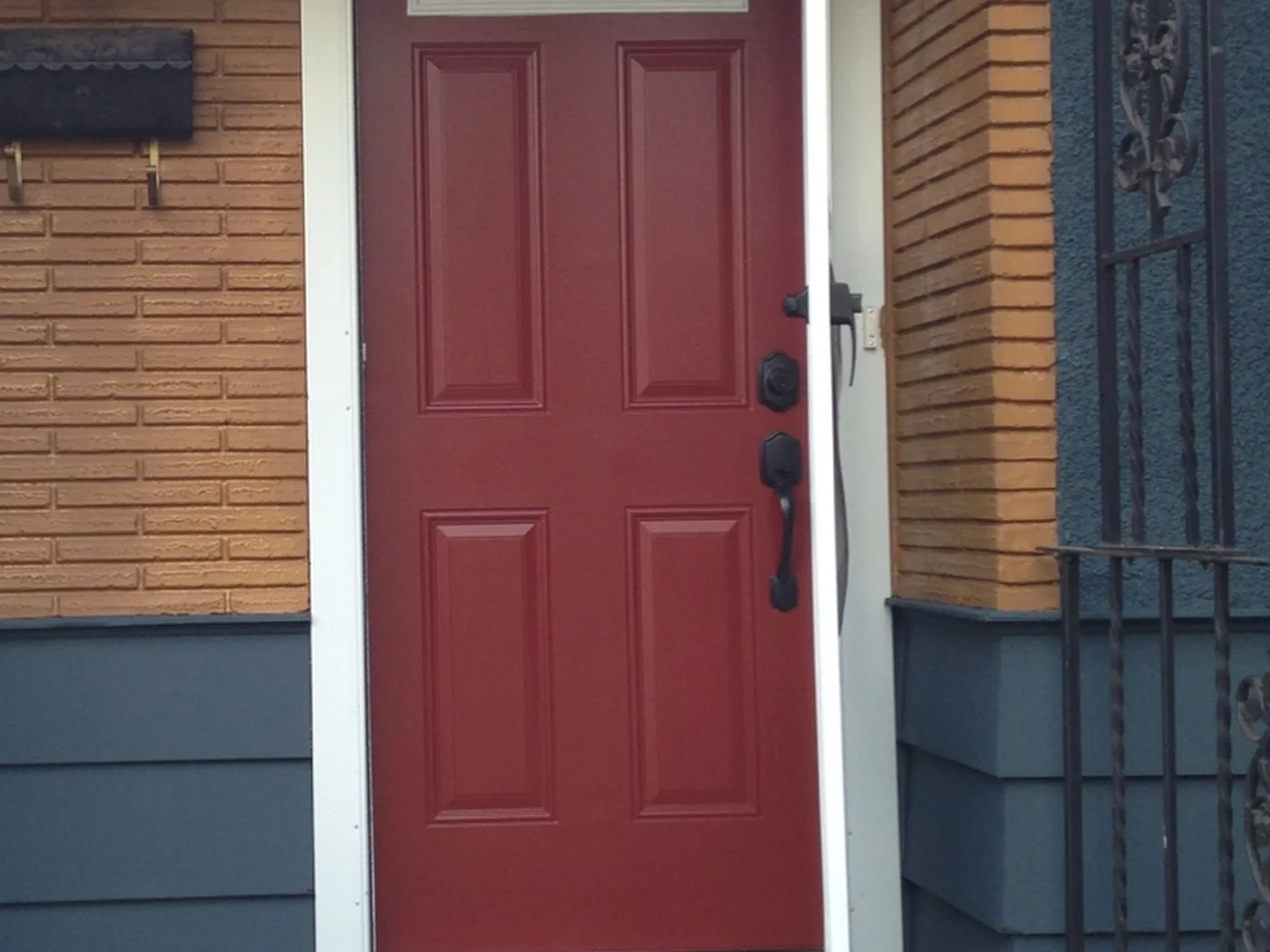 Painted red front door beneath a covered porch with metal railings in Edmonton