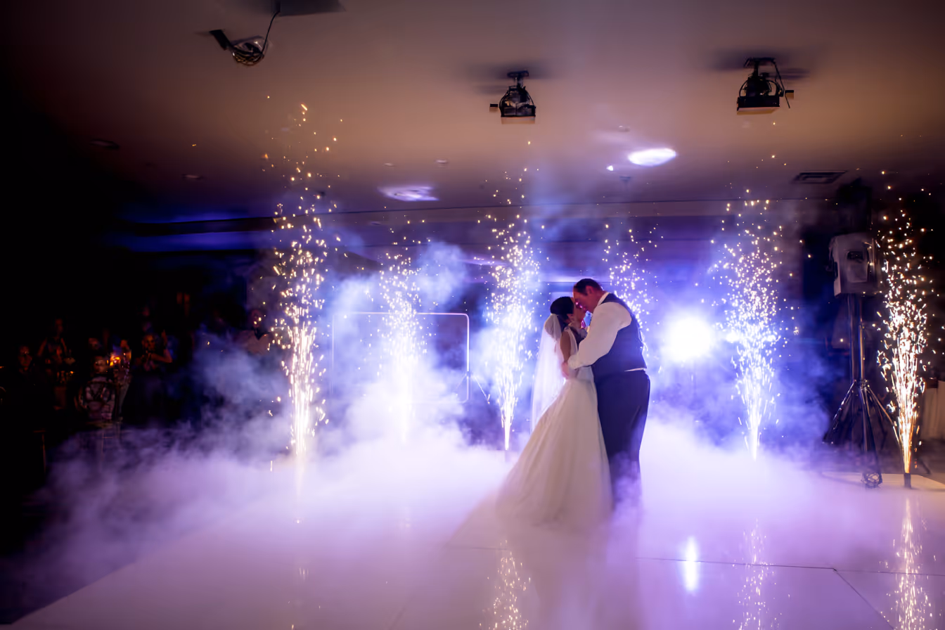 Bride and groom sharing a romantic dance surrounded by smoke and sparklers on a wedding dance floor.