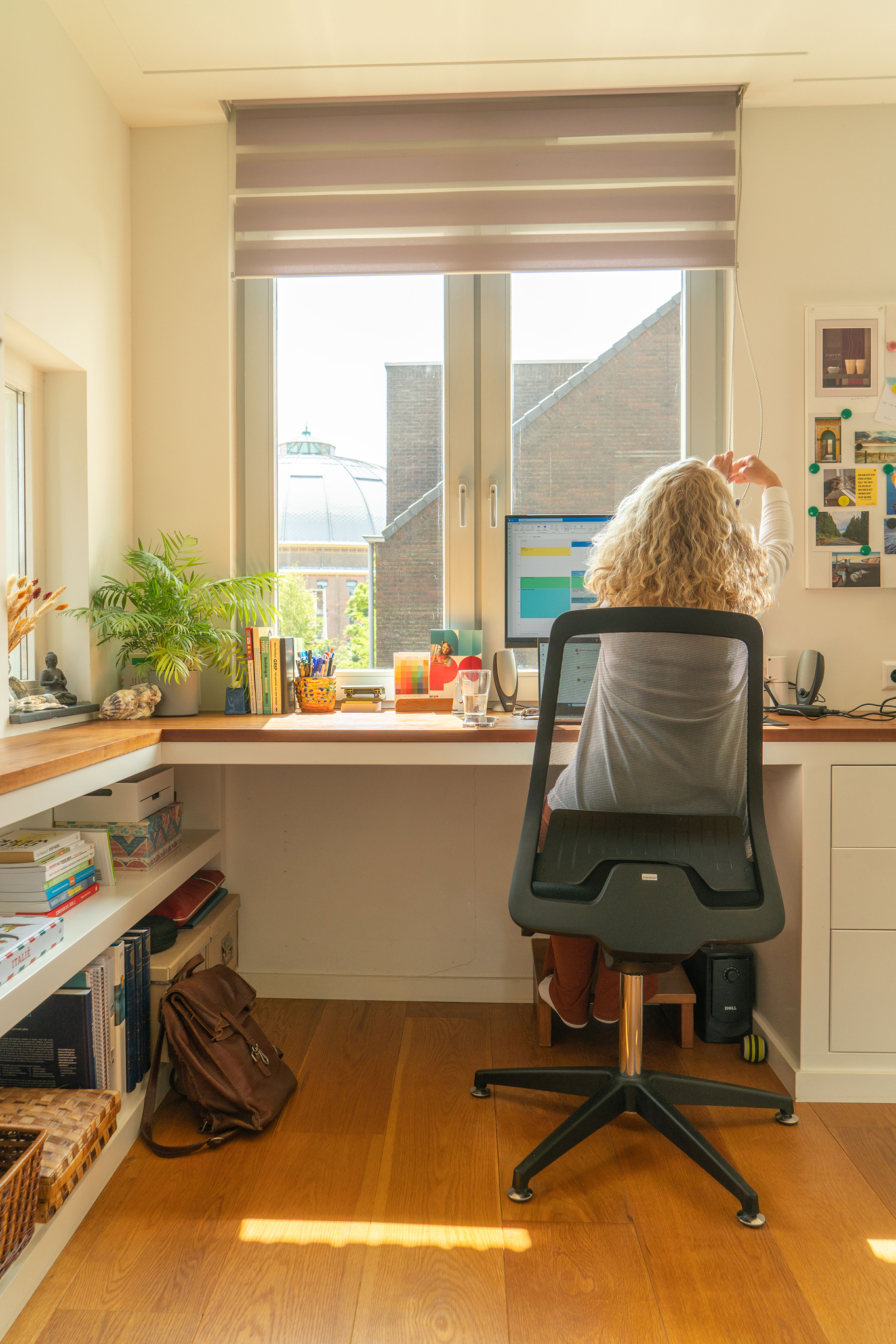 Linda Verkooij doet rolgordijn op werkplek omhoog voor uitzicht op overzicht.