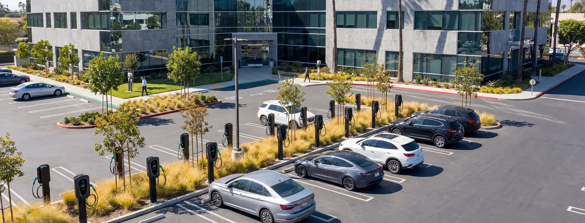 Office building parking lot with electric vehicle charging stations and cars parked in spaces.