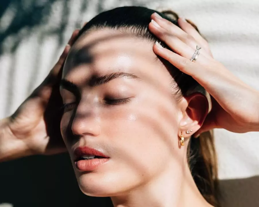 A woman with her eyes closed and her hand on her head.