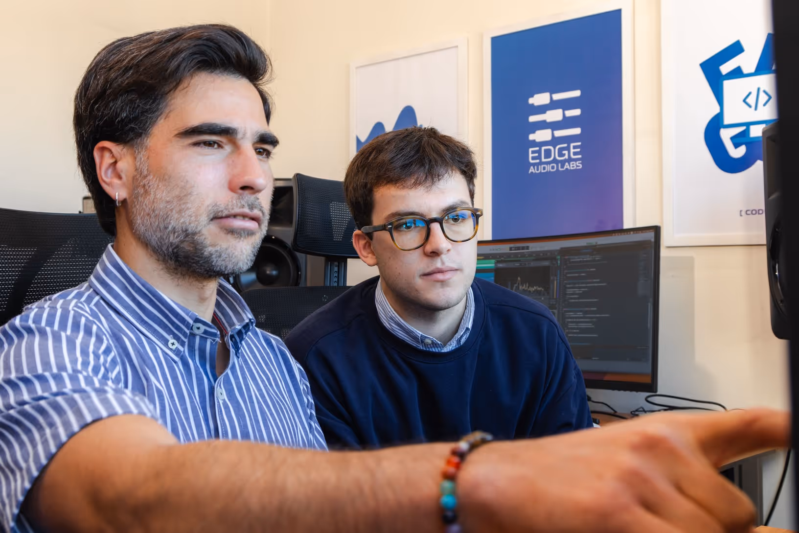 Team members from Edge Audio Labs collaborating on a project in the office, focused on a computer.
