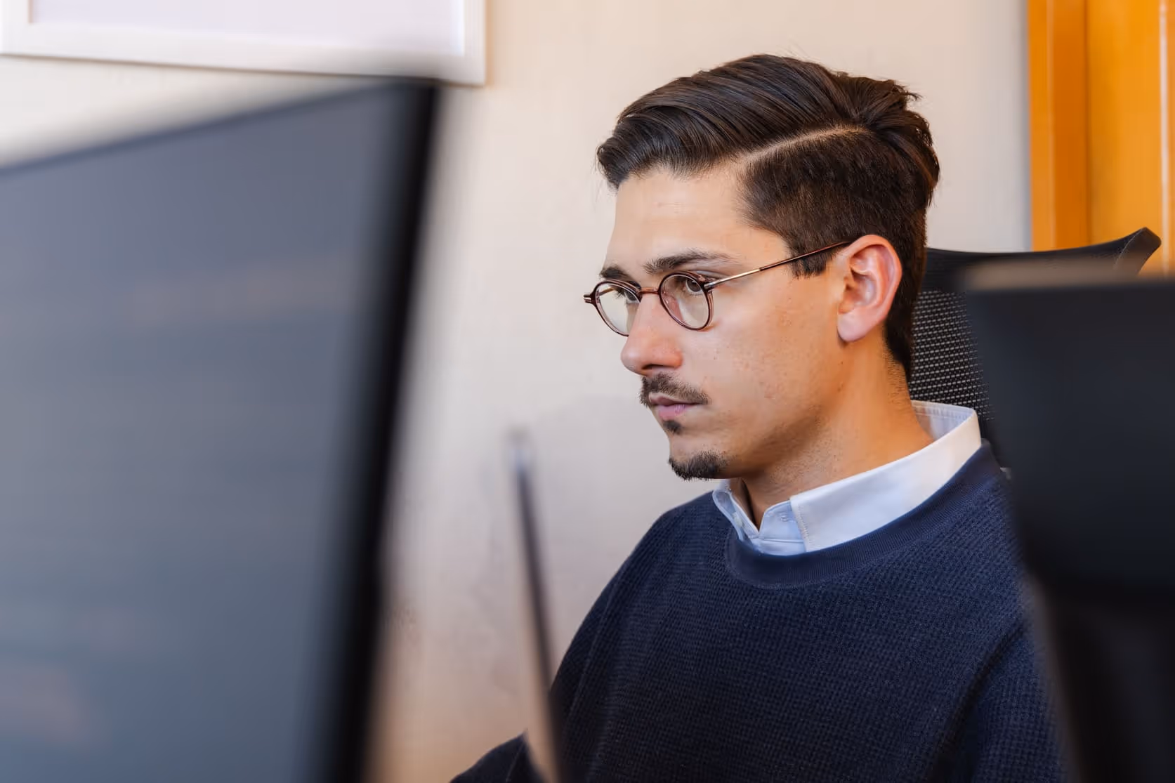 Joaquín Saavedra, CEO of Edge Audio Labs, intently focused on a computer monitor, demonstrating the company's commitment to hands-on leadership and deep engagement in the development of cutting-edge audio technology.