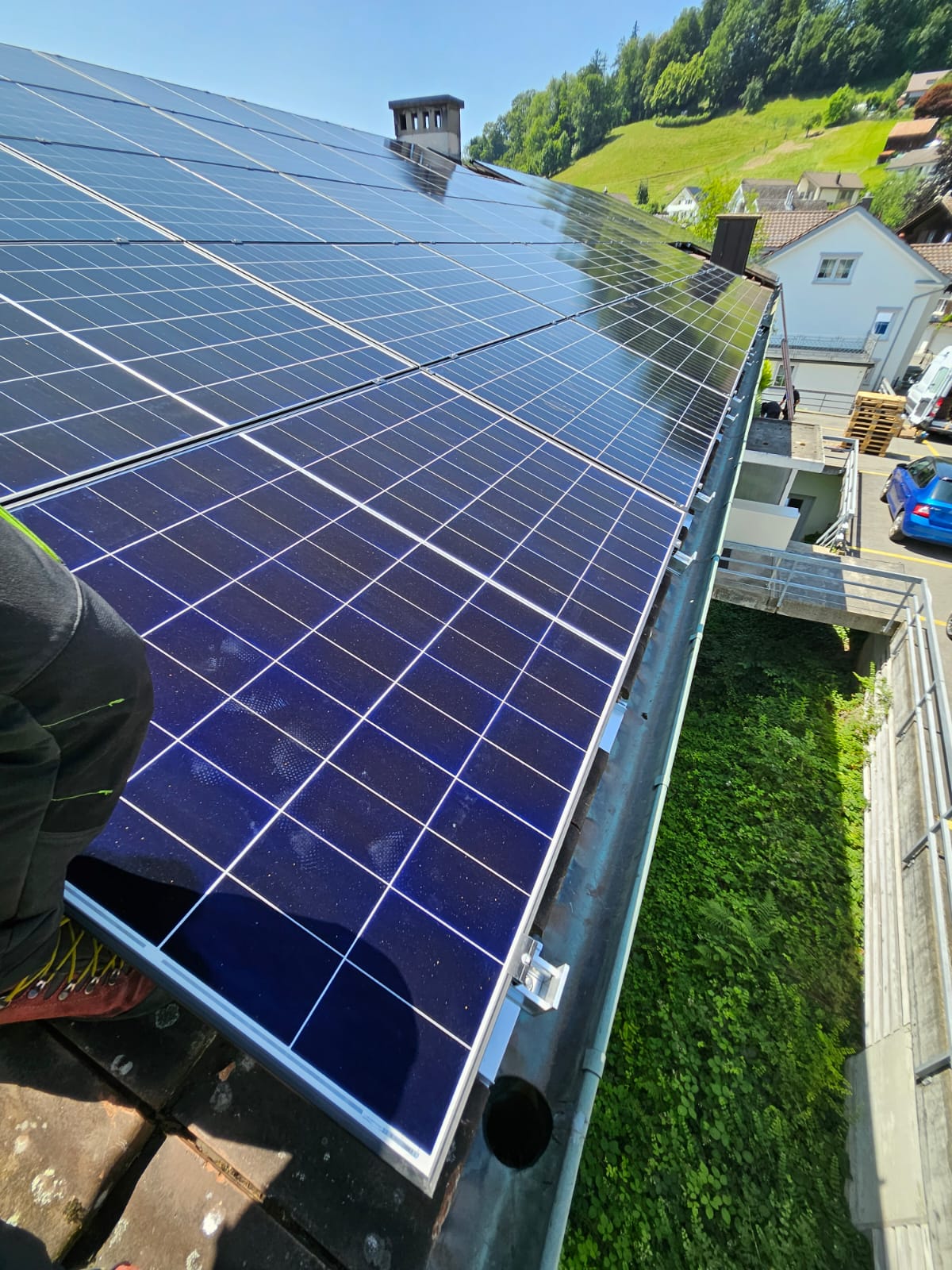Vollständig installierte PV-Anlage auf dem Dach mit Ausblick auf Bäume und Hügel
