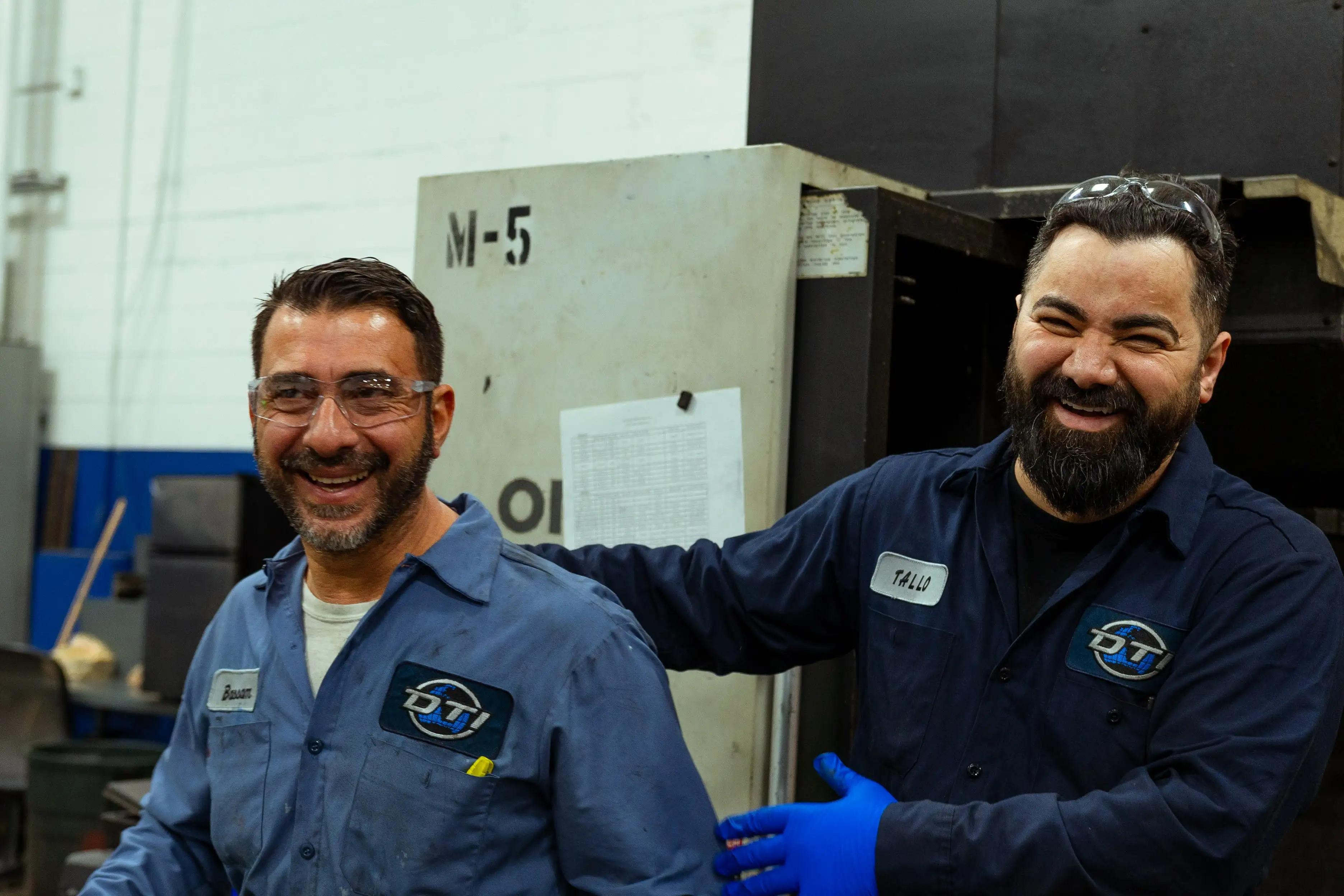 Two DTI Engineers laughing together while working the tooling facility. 
