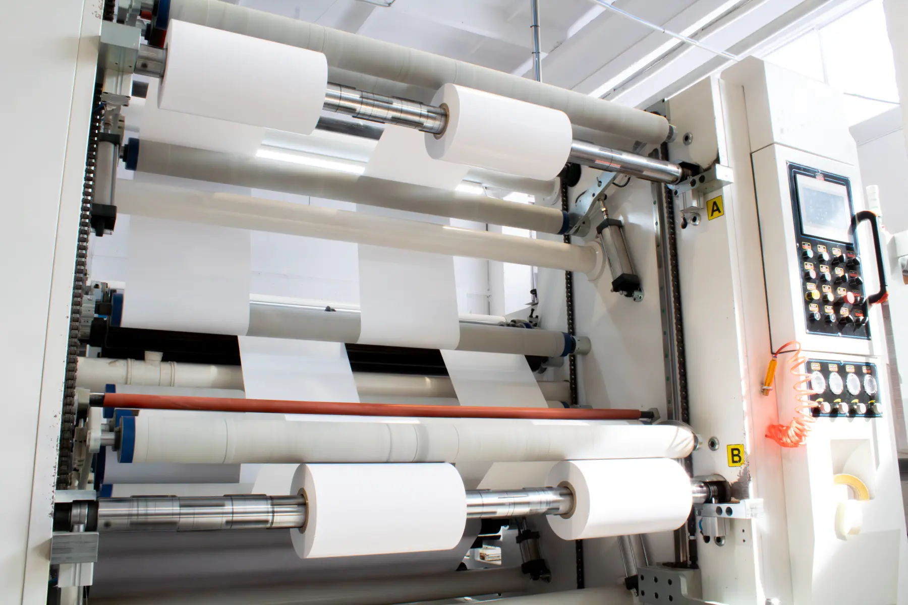Industrial high-precision slitting and rewinding machine processing large paper and film rolls.