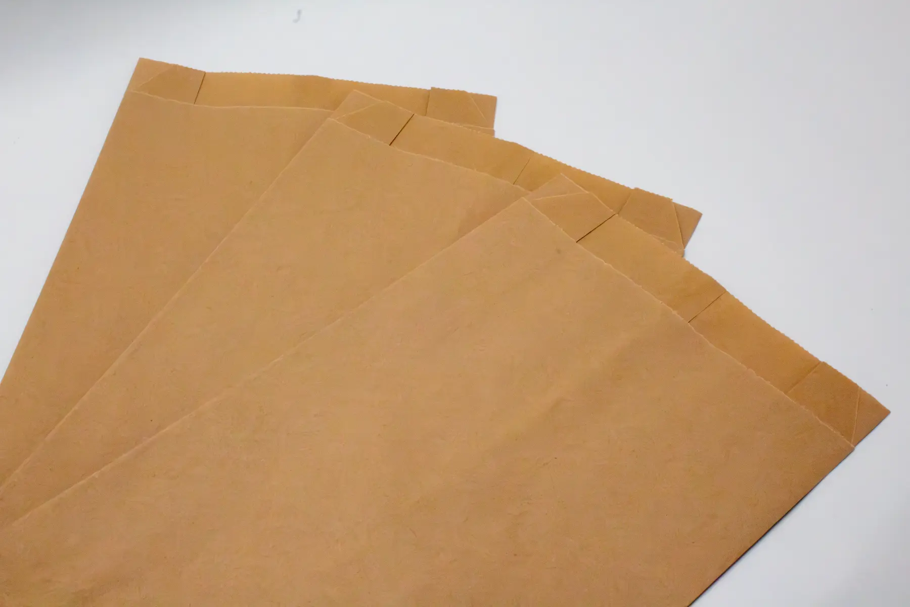 Stapel skalierbarer Flachboden-Papierbeutel, gefertigt mit engen Maßtoleranzen für automatisierte Ausgabesysteme.