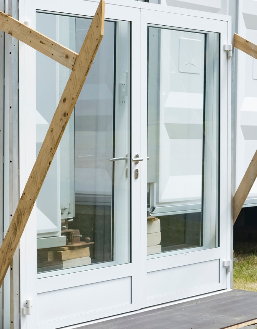 Reused white door and glass window frame on construction site – showcasing circular construction with Enke platform