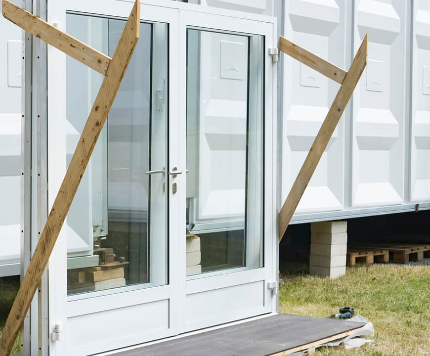 Reused white door and glass window frame on construction site – showcasing circular construction with Enke platform